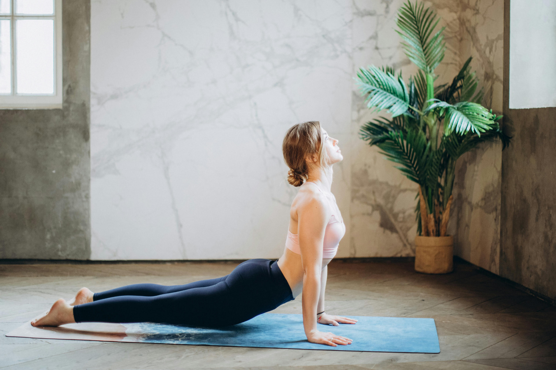 Kvinna i yogaposition i ljus lokal